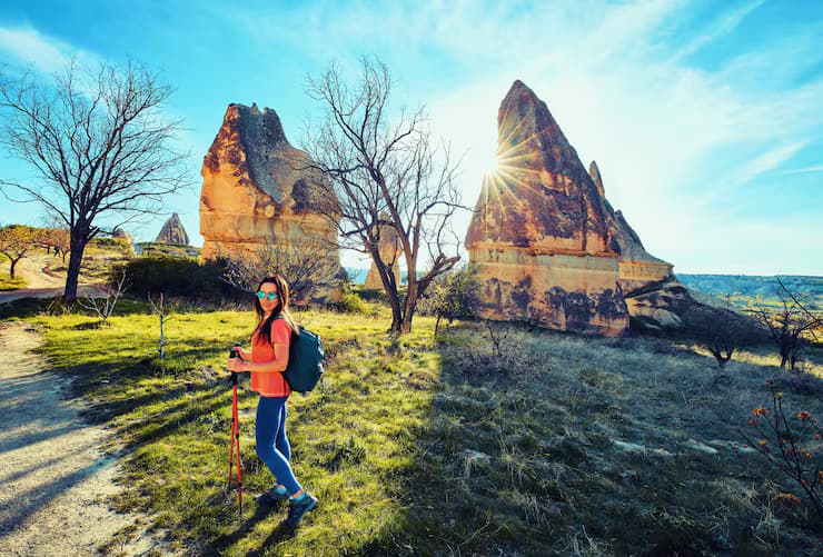 Female hiker posing near unique rock formations in a sunny valley